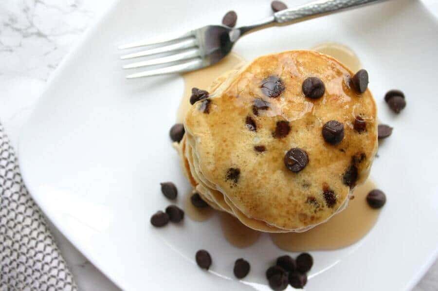 overhead view of chocolate chip pancakes stacked on a white plate