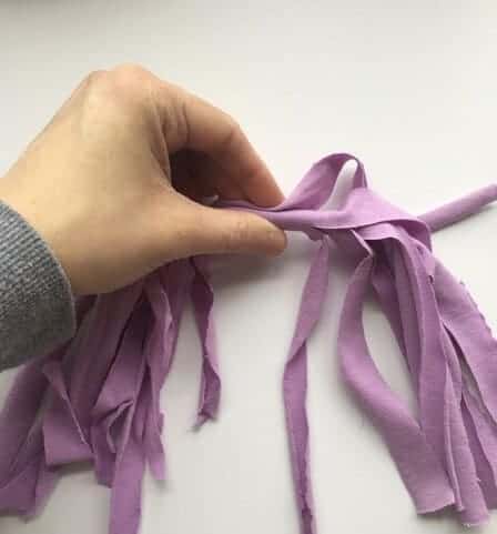 woman's hand holding a purple fabric tassel at the top