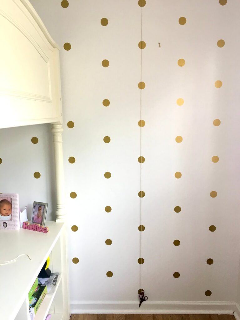 hanging gold polka dot wall stickers in rows in an even pattern