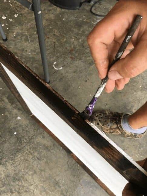 man staining sides of trim boards for DIY wood signs