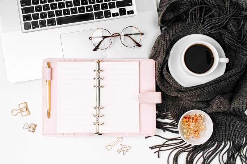 pink planner on a desk with computer and coffee