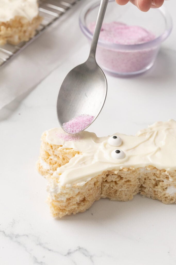 spooning pink sugar on the ears of a bunny cereal treat