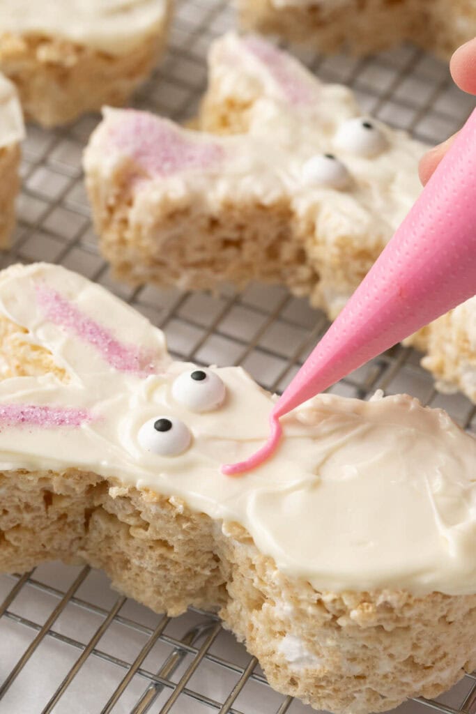 piping pink icing for a smile on a Easter bunny rice krispies treat