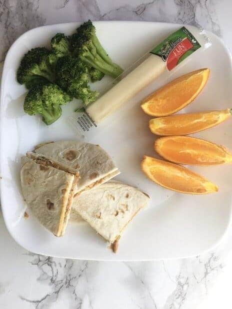 orange slices, string cheese, broccoli, and peanut butter banana quesadilla on a plate