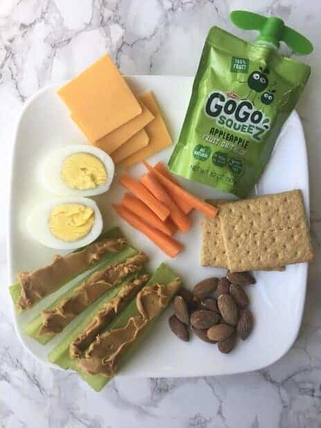 snack plate with hard boiled eggs, celery, carrots, graham crackers, and apple sauce