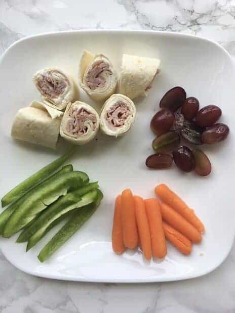 green pepper strips, carrots, grapes, and turkey roll ups on a plate