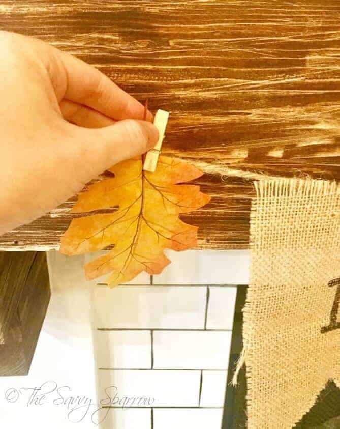 woman's handing clipping an orange leaf to a burlap banner