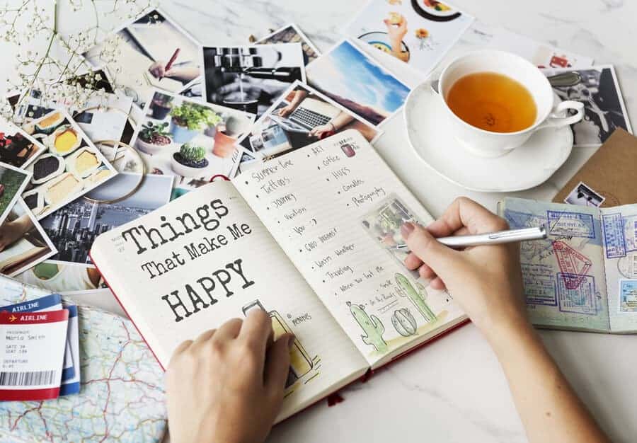 lady writing in a bullet journal with photographs scattered in the background