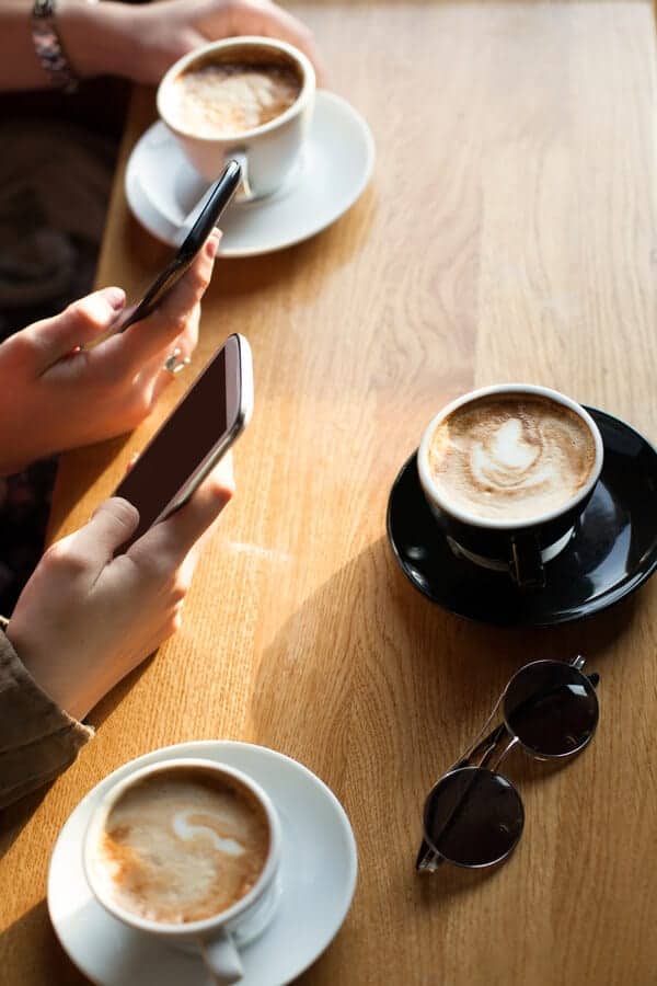 teens holding cell phones in a coffee shop