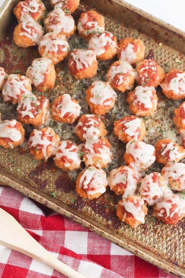 cooked parmesan chicken bites on a baking sheet with a red and white towel