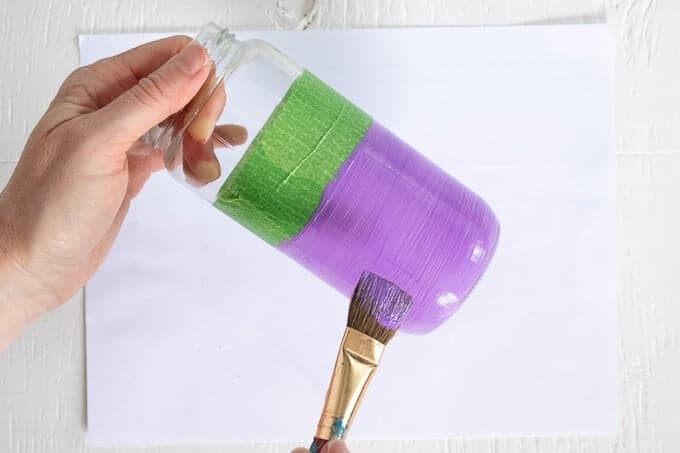 woman's hand painting glass jar purple