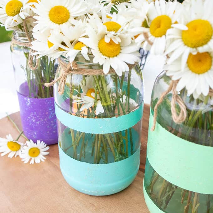 painted stripe mason jars used as vases with daisies inside