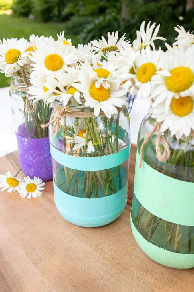 painted stripe mason jars used as vases with daisies inside