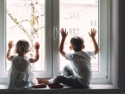 two bored kids looking out a window