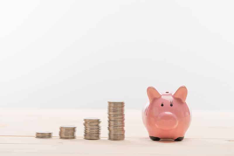 stacks of coins next to a piggy bank