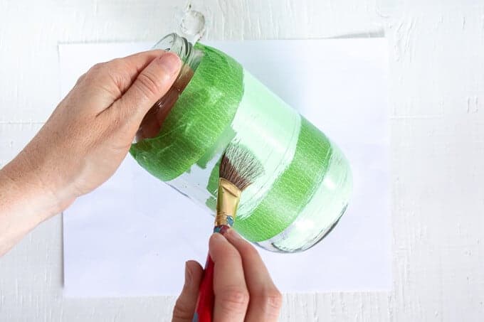 woman's hands painting mason jar