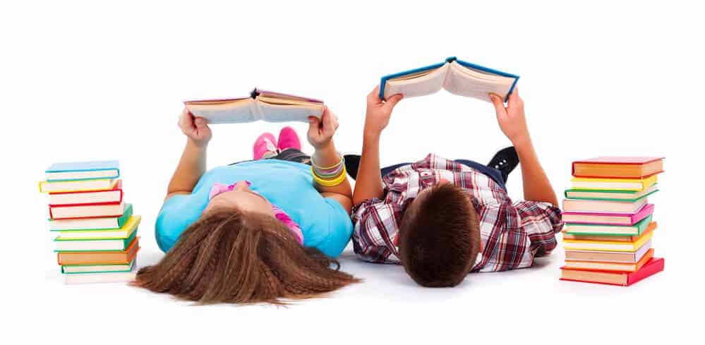 2 kids reading while laying down near a stack of books