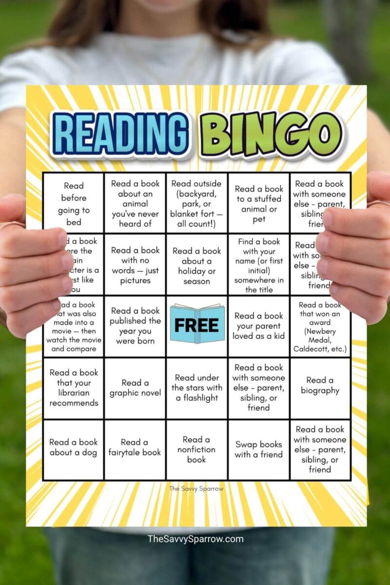 girl holding a Reading Bingo card with different reading challenges in a grid