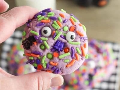 child's hand holding a Halloween cookie with sprinkles