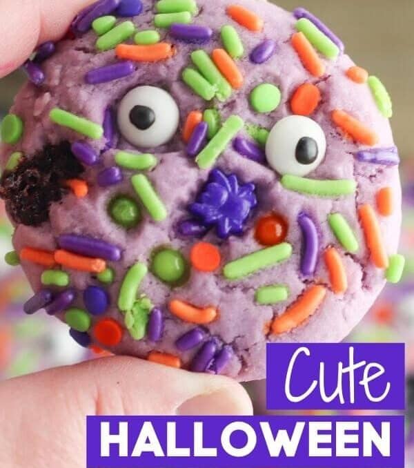 child's hand holding a Halloween cookie with sprinkles with text cute Halloween cookies
