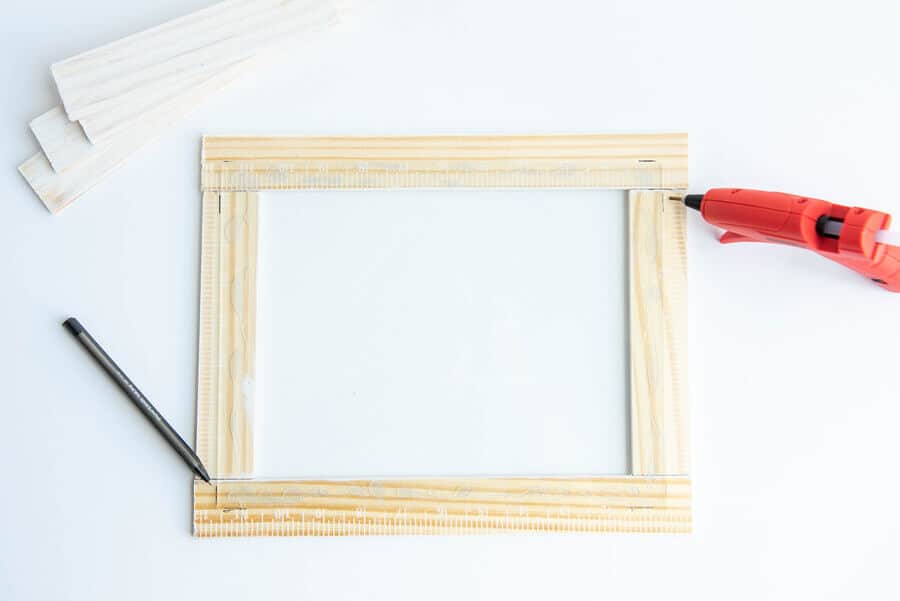 paint sticks in a rectangle shape with glass on top and glue gun