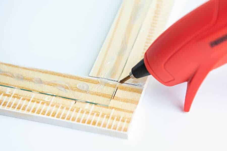 close up view of hot glue gun and hot glue under glass of wood frame