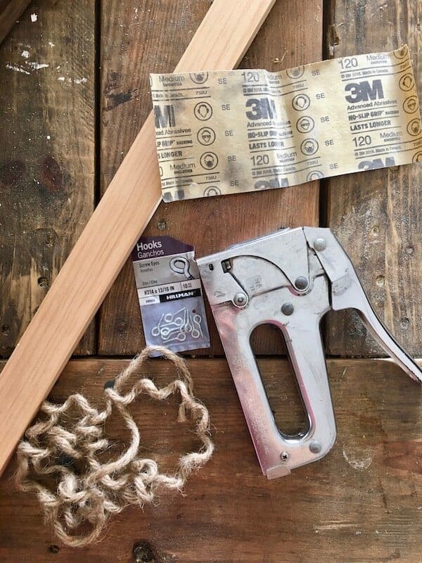 staple gun, eye screws, sand paper, board, and twine on a table