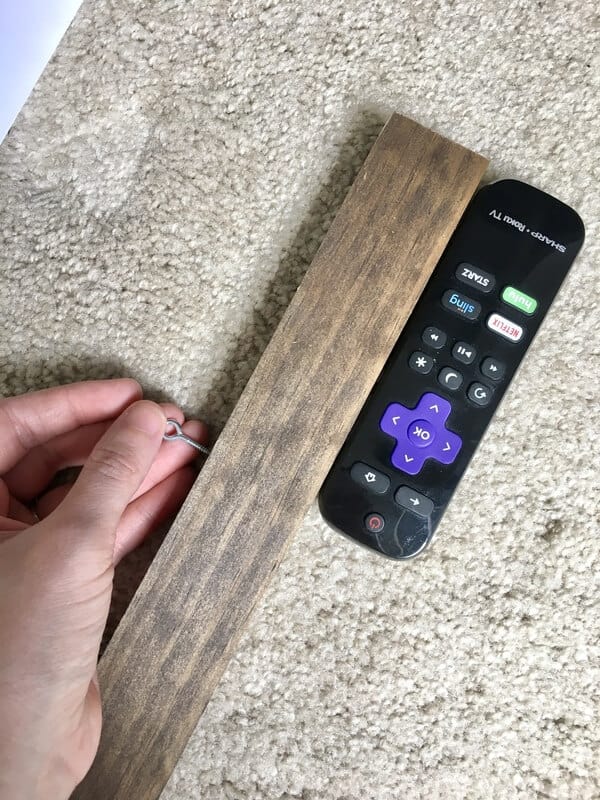 woman's hand screwing an eye screw into a board