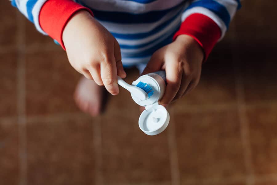 child putting toothpaste on a toothbrush