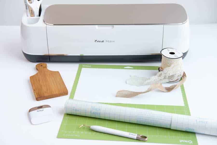 Cricut maker, wedding tool, vinyl, grip mat, and mini cutting board on a table