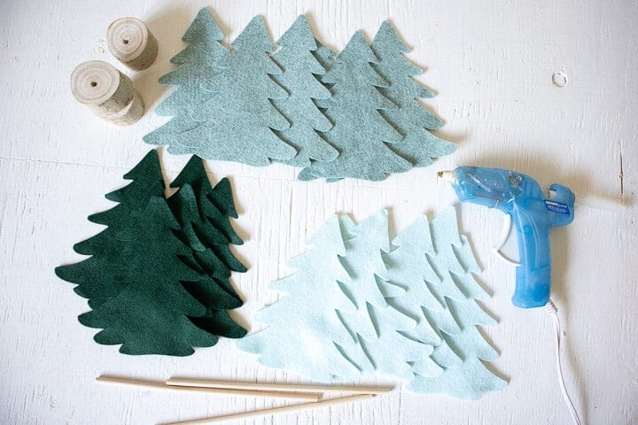 felt Christmas tree shapes on a table with a glue gun