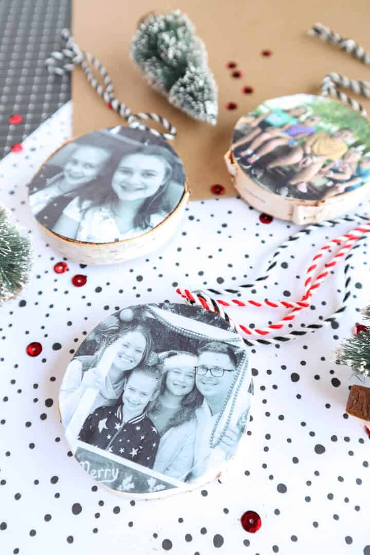 DIY wood slice photo ornaments laying on a Christmas background