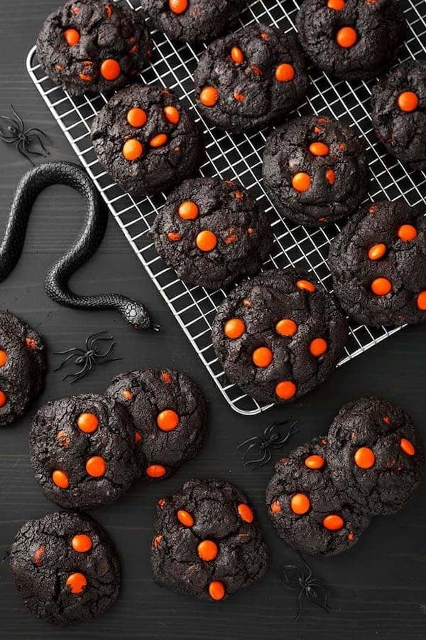 black colored cookies with orange candies on top