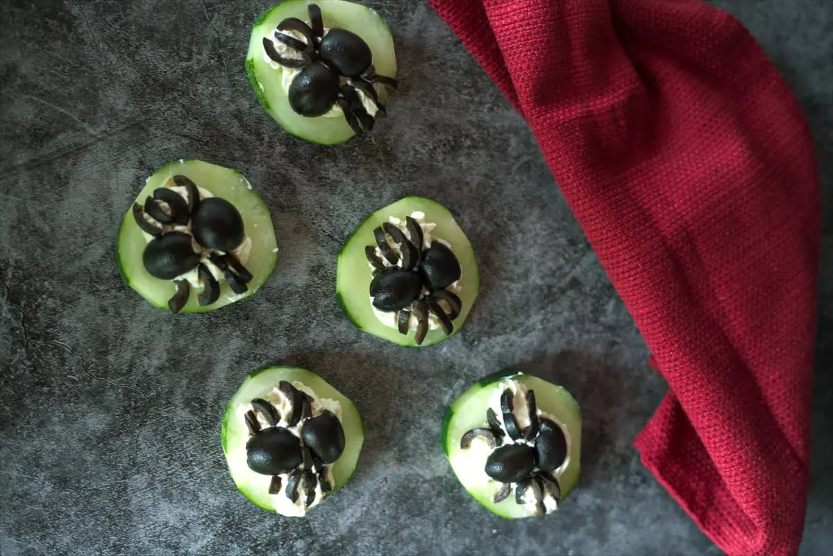 cucumber slices with cream cheese and spider shaped olives on top