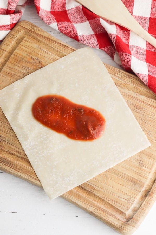 pizza sauce spread in the middle of an egg roll wrapper