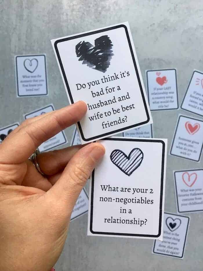 woman's hand holding 2 conversation cards for couples