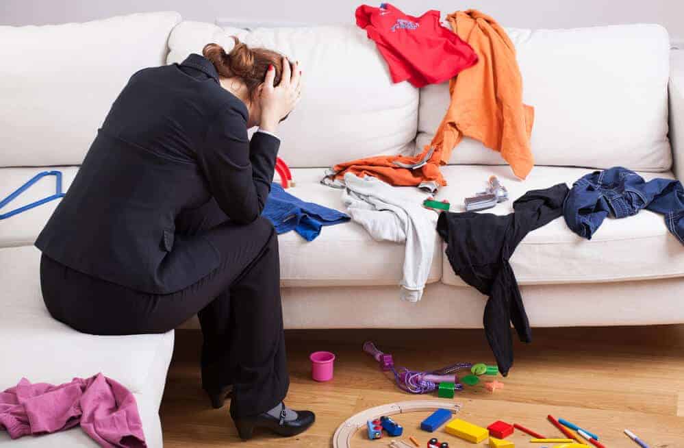 woman sitting on couch overwhelmed by clutter