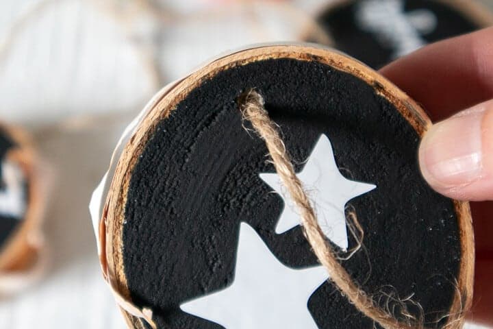 woman putting a twine loop on a wood slice ornament