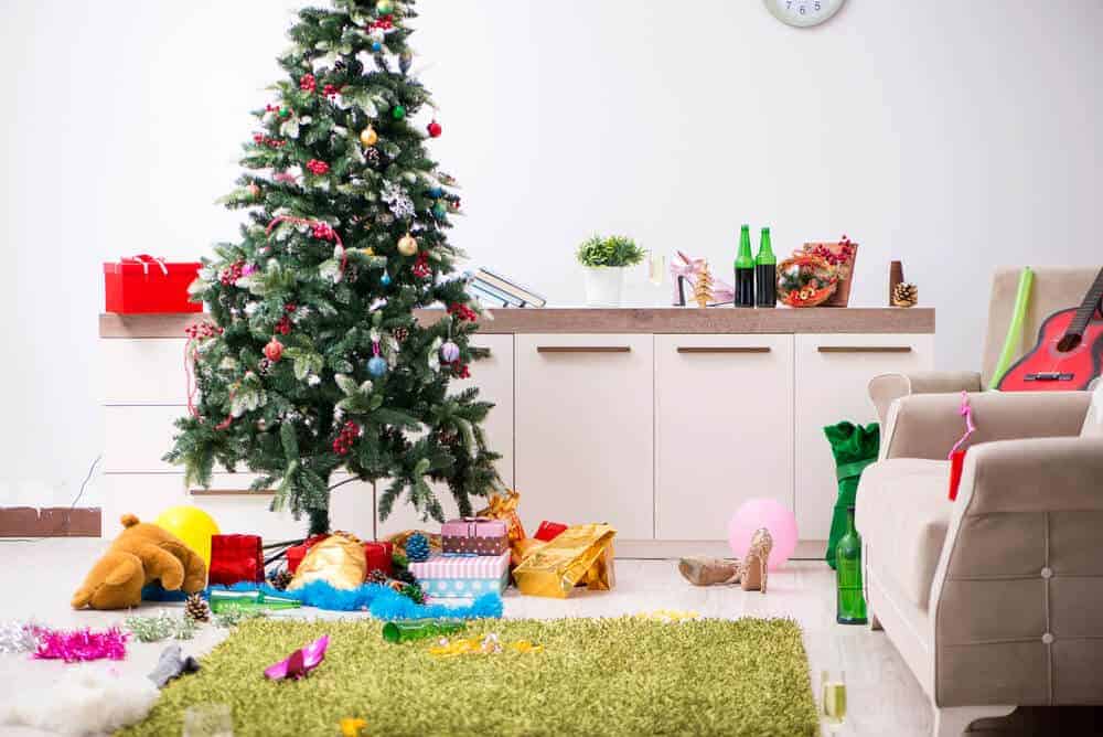 messy living room with Christmas tree and gifts