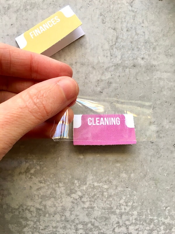 woman's hand putting packing tape on a DIY binder tab