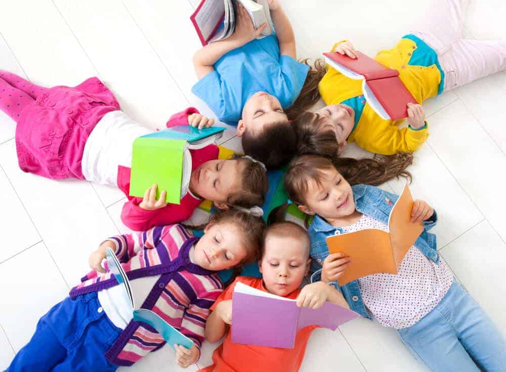 kids laying on the ground reading books