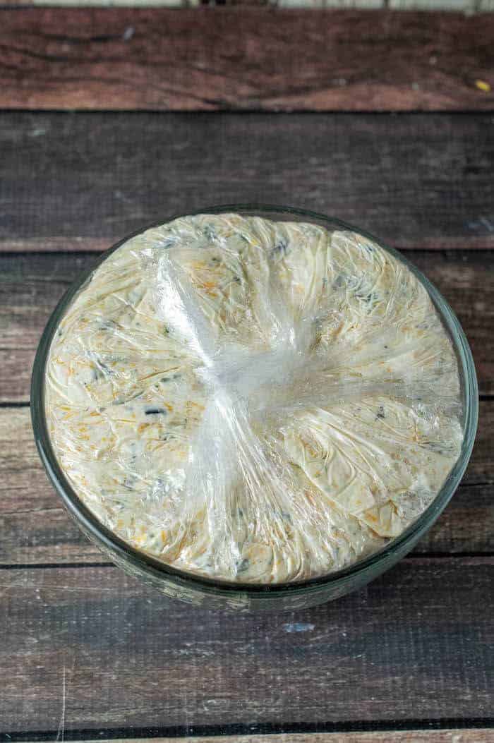 cheeseball mixture in a bowl with plastic wrap