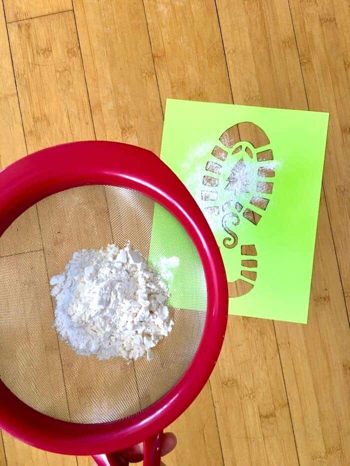 sifting flour on top of a boot print stencil