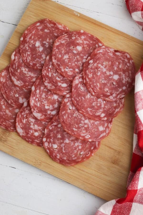 salami slices in a layer on a cutting board