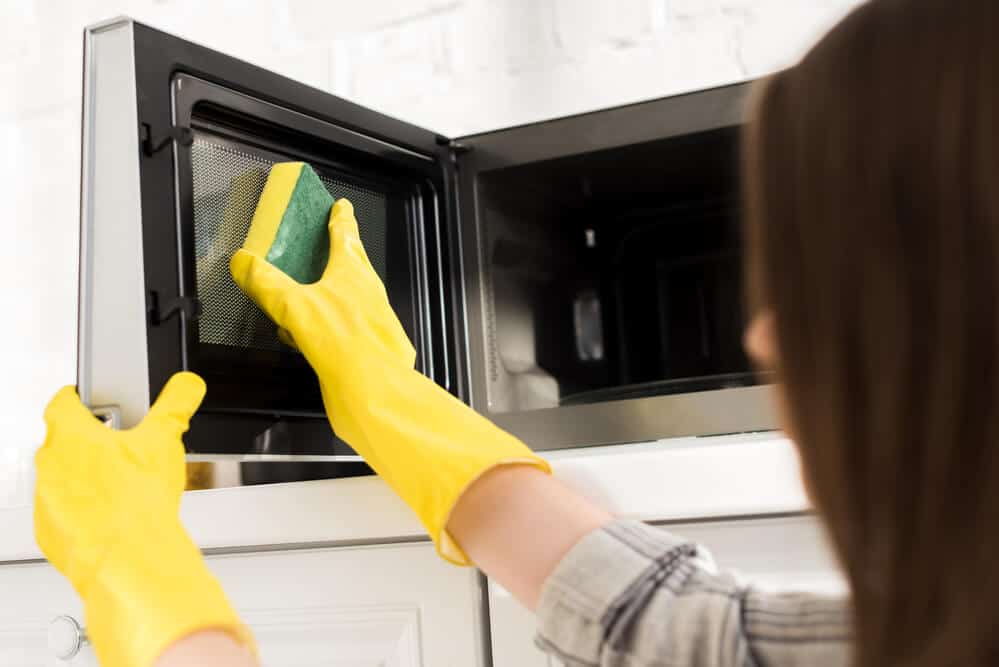 woman cleaning a microwave