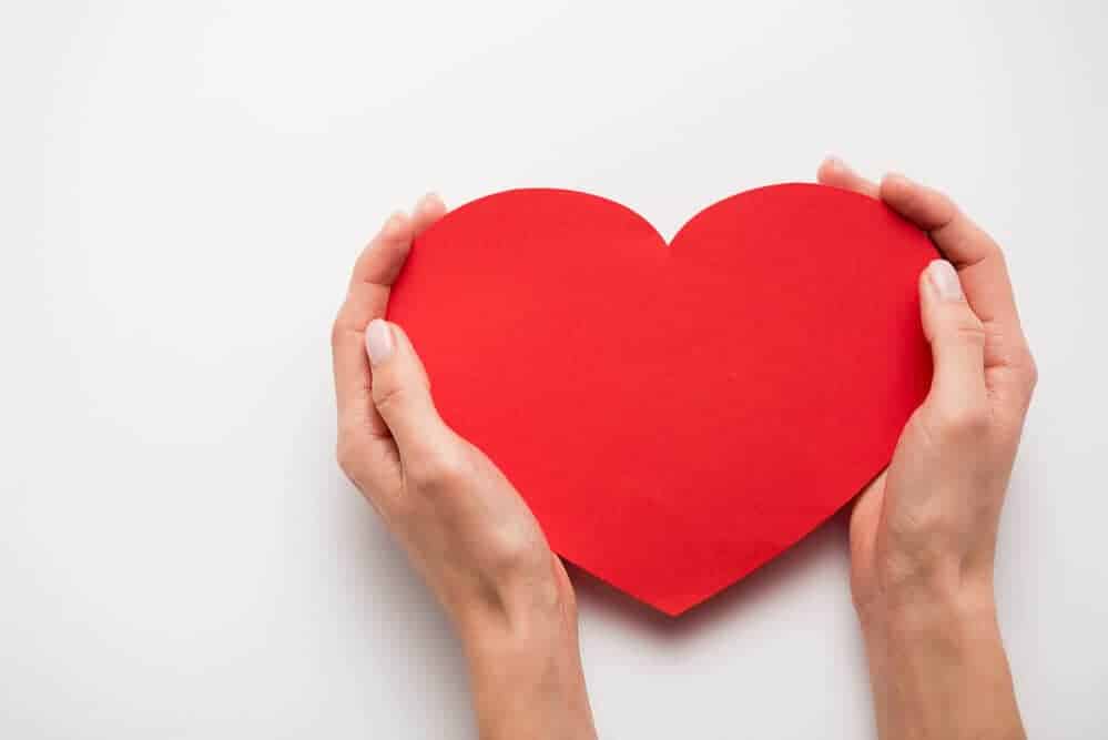 woman's hands holding a paper heart