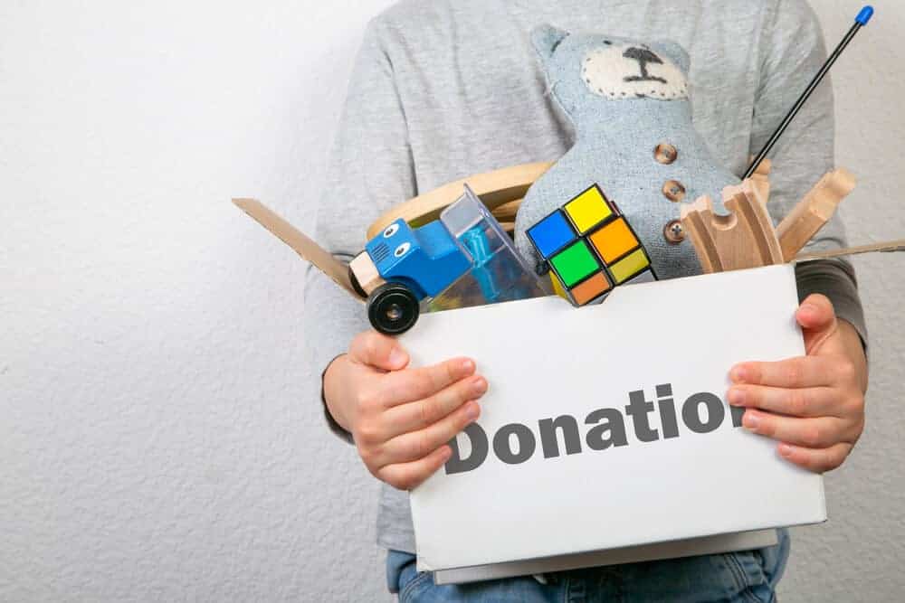 boy holding a box of toys labeled donations