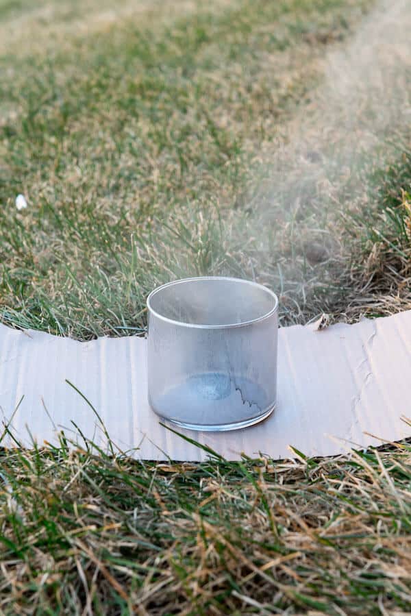 spray painting a glass vase to make DIY mercury glass