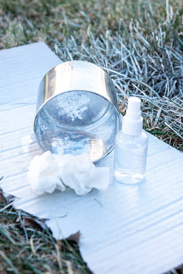 paper towel and spray bottle near a glass vase sprayed with mirrored spray paint