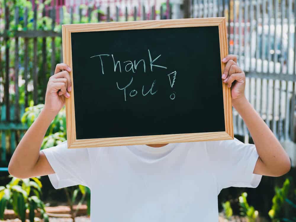 boy holding a chalkboard sign that says thank you